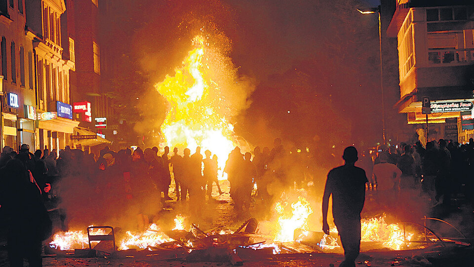 Manifestantes caminan entre barricadas incendiadas en el distrito de Schanzenvietel, de Hamburgo, Alemania.