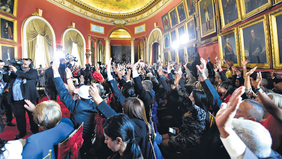 Miembros de la Asamblea Nacional Constituyente levantan sus manos durante su instalación en el Congreso venezolano.