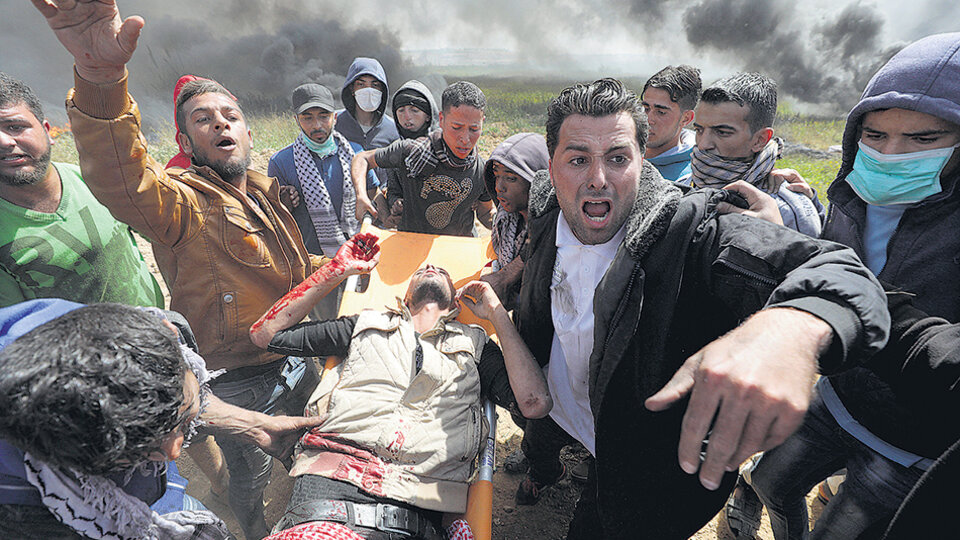 Manifestantes palestinos transportan en camilla a un activista herido en la frontera con la Franja de Gaza.