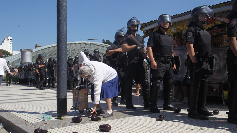 Una mujer intenta recuperar alguna berenjena tras la brutal represión policial.