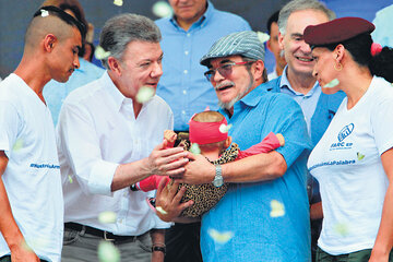 El presidente Santos saluda a una bebé que es sostenida por el máximo líder de las FARC, Londoño. (Fuente: EFE)