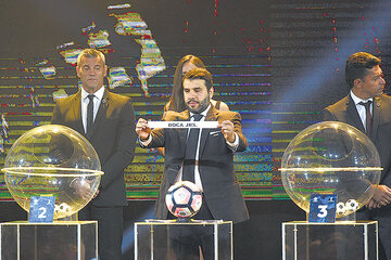 Hugo Figueredo muestra la cinta con el nombre de Boca durante el sorteo. (Fuente: AFP)