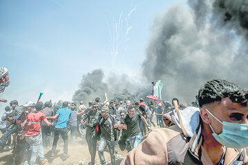 Manifestantes corren para protegerse del gas lacrimógeno anteayer en la frontera entre Israel y la Franja de Gaza. (Fuente: EFE)