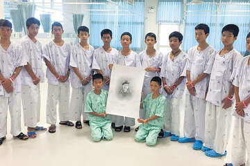 Los 13 jóvenes tailandeses, vestidos con sus batas, en el hospital de Chiang Rai, en un homenaje a Saman Kunan, el rescatista fallecido. (Fuente: AFP)