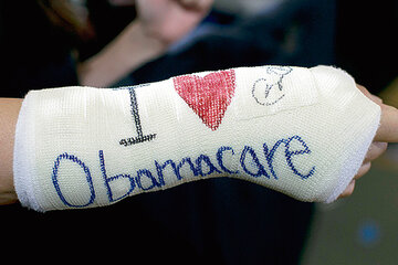 En Boston, ayer, un beneficiario de Obamacare muestra su apoyo al programa de salud en el yeso de su muñeca.