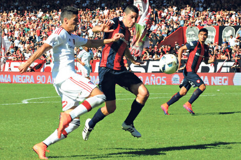 Amoroso y Merlini se enfrentan dentro del área de San Lorenzo en uno de los pasajes del primer tiempo del duelo jugado en Rosario.