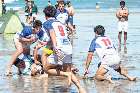 Los jugadores de beach rugby, peleando por quedarse con la ovalada chapoteando en el agua.