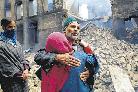 Abrazo frente a un edificio destruido por el fuego cruzado en la Cachemira india.