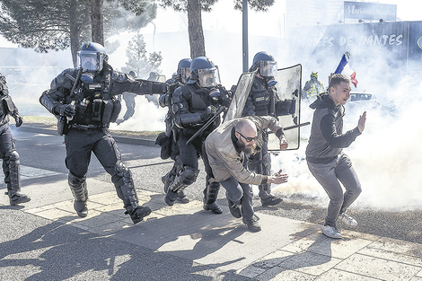 Chalecos amarillos levantan las manos y escapan de la policía en Saint-Herblain, cerca de Nantes. (Fuente: AFP)