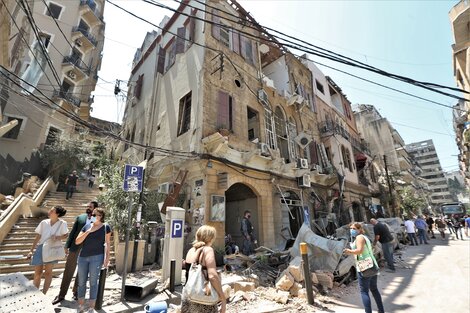 Un grupo de personas camina delante de edificios dañados por las explosiones en el barrio Achrafyeh Rmeil de Beirut.