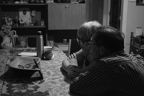 Una pareja mayor contempla con ternura una pantalla apoyada en la mesa del comedor. Del taller de fotografía de La Vigil.