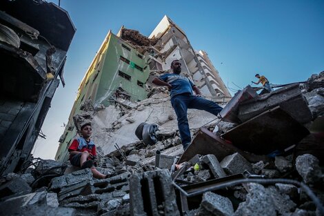 Palestinos caminan sobre los escombros de un edificio destruido en Ciudad de Gaza. 