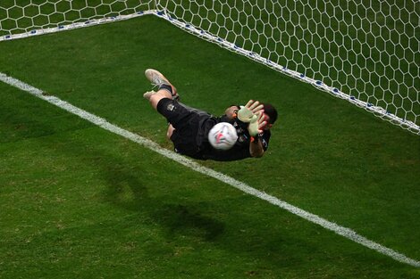 Dibu Martínez en pleno vuelo, para controlar el penal de Yerry Mina.