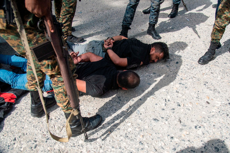 Policías custodian hoy a dos sospechosos de haber participado en el asesinato del presidente haitiano. 