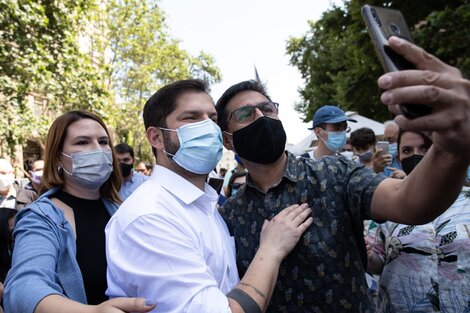 Boric (c), se toma fotos con ciudadanos durante un acto en el centro de Santiago.