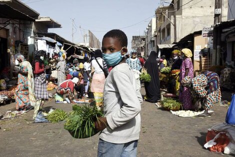 Un chico que vende verduras en Dakar se defiende del virus con un tapabocas.