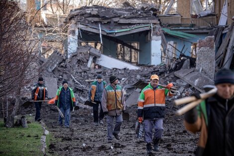 Una cuadrilla detrabajadores camina delante de la escuela bombardeada en Kramatorsk.