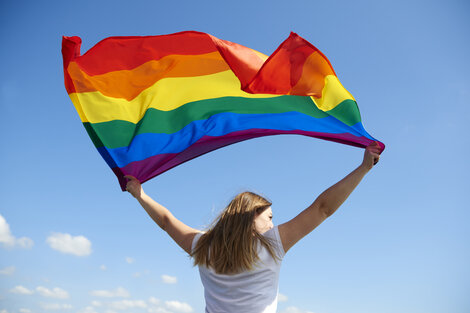 Una mujer sostiene la bandera del orgullo. Imagen: Freepik