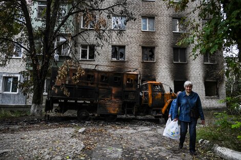 Dos mujeres caminan frente a una casa bombardeada en Balakliya, región de Kharkiv.