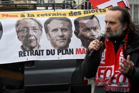 El líder sindical Fabrice Lerestif habla frente a un banner con las caras de la premier Borne, el presidente Macron y el ministro de Trabajo, Dussopt.  