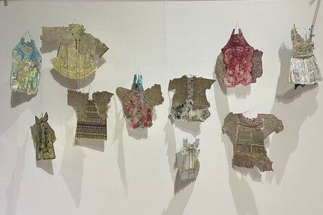 Obra de Claudia Contreras con ropa usada de bebé, mapas de la Argentina, acuarela. Abajo: Vista parcial de la muestra de Gabriela Cassano, gráfica y arte textil.
