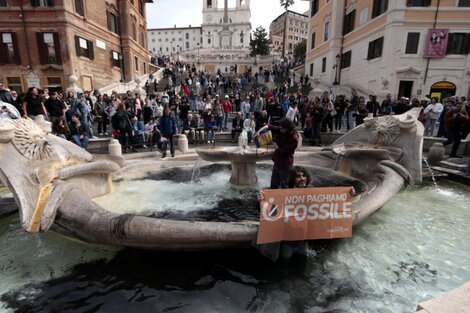 Activistas ambientales al momento de vandalizar una fuente en pleno centro de Roma. "No paguemos fósiles", dice el cartel. 