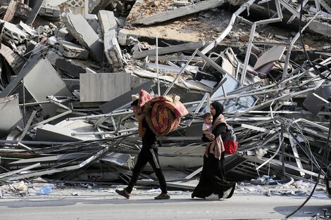 Una familia abandona una Cuidad de Gaza en ruinas con lo que puede cargar.