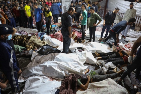 Palestinos rodean cadáveres de lasvíctimas delbombardeo al hospital.