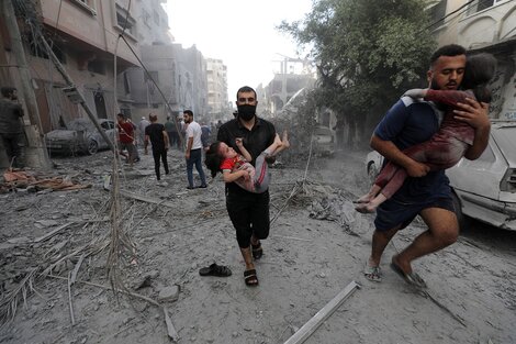 Dos hombres palestinos trasladan en brazos a niños heridos tras un ataque aéreo israelí. 