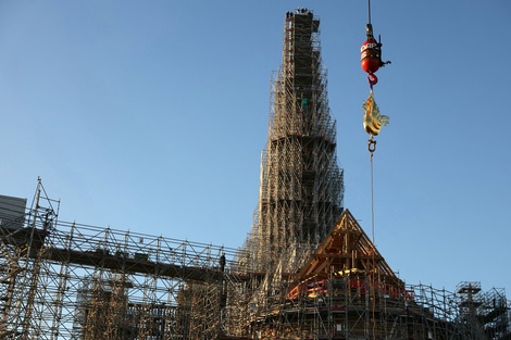 El nuevo gallo dorado con reliquias es izado por una grúa para ser instalado en lo alto de la aguja de la catedral de Notre Dame. (Fuente: AFP)