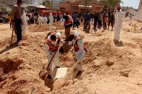 Equipos médicos trabajan en una fosa común en el predio del hospital Naser.  (Fuente: EFE)