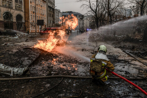 Bomberos ucranianos apagan llamas después un ataque misilístico ruso en Kiev. 