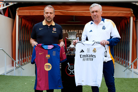 Hansi Flick y Carlo Ancelotti posan con casacas de sus equipos junto al trofeo