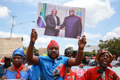 Miembros de la comunidad congoleña en Sudáfrica sostienen carteles y una pancarta con los rostros del presidente sudafricano y del presidente de la República Democrática del Congo (RDC). Imagen: Phill Magakoe/AFP