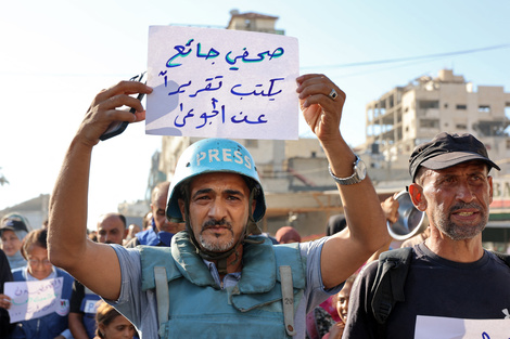 Un cronista sostiene un cartel en árabe que dice "un periodista hambriento escribe un reportaje sobre los hambrientos" en Ciudad de Gaza.