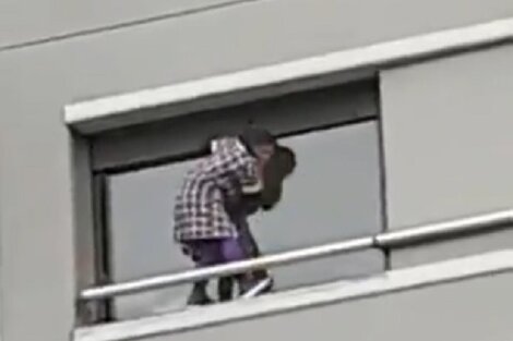 La mujer que limpia la ventana, del lado de afuera, en un sexto piso. 