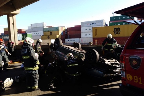 Bomberos revisan el auto tras el choque y vuelco en Puente Avellaneda.