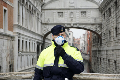 Un policía con barbijo monta guardia antes de la suspensión del carnaval en Venecia.