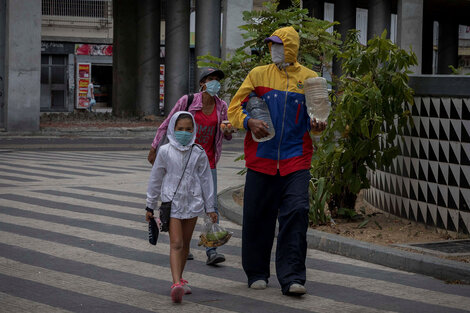 Una familia camina por las calles de Caracas cargando agua y fruta. (Fuente: EFE)