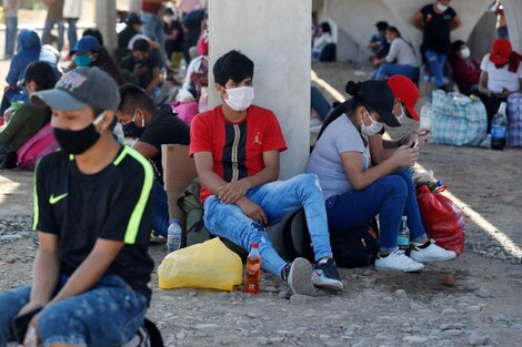 Un grupo de migrantes descansa bajo un puente de la ruta Panamericana Sur cerca de Lima.  