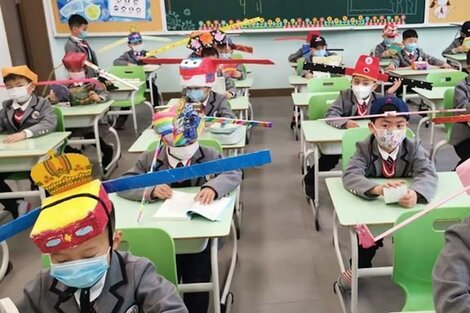 Una escuela de Zheijiang, China, donde los niños usan sombreros de cartón, con varillas a los costados para el distanciamiento.