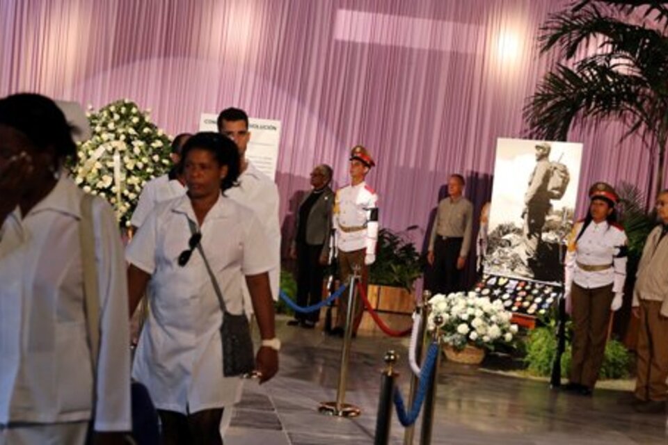 La gente rinde tributo a Fidel Castro ante un gran retrato de líder dispuesto en un discreto altar con flores blancas. (Fuente: EFE)
