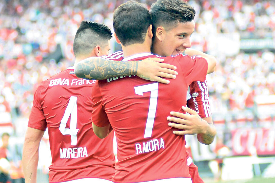 Driussi, Moreira y Mora abrazados al gol y a la victoria con el Monumental como escenografía. (Fuente: DyN)