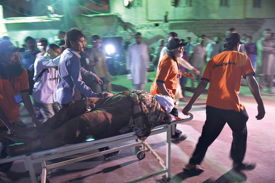 Rescatistas paquistaníes evacuan a un hombre herido del templo después del atentado.