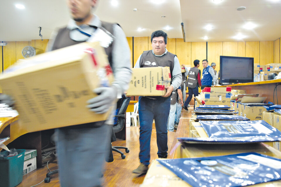 Miembros del Consejo Nacional Electoral cargan cajas con votos durante el conteo en Quito. (Fuente: EFE)