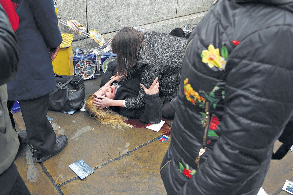 Una de las personas heridas por el atacante yace en el suelo mientras testigos intentan socorrerla. (Fuente: Télam)