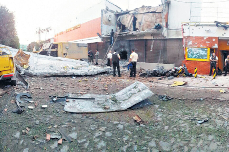 La explosión hizo volar el edificio de la empresa. A la derecha, un blindado entre escombros, uno de los autos quemados y uno de los sofisticados fusiles utilizados.