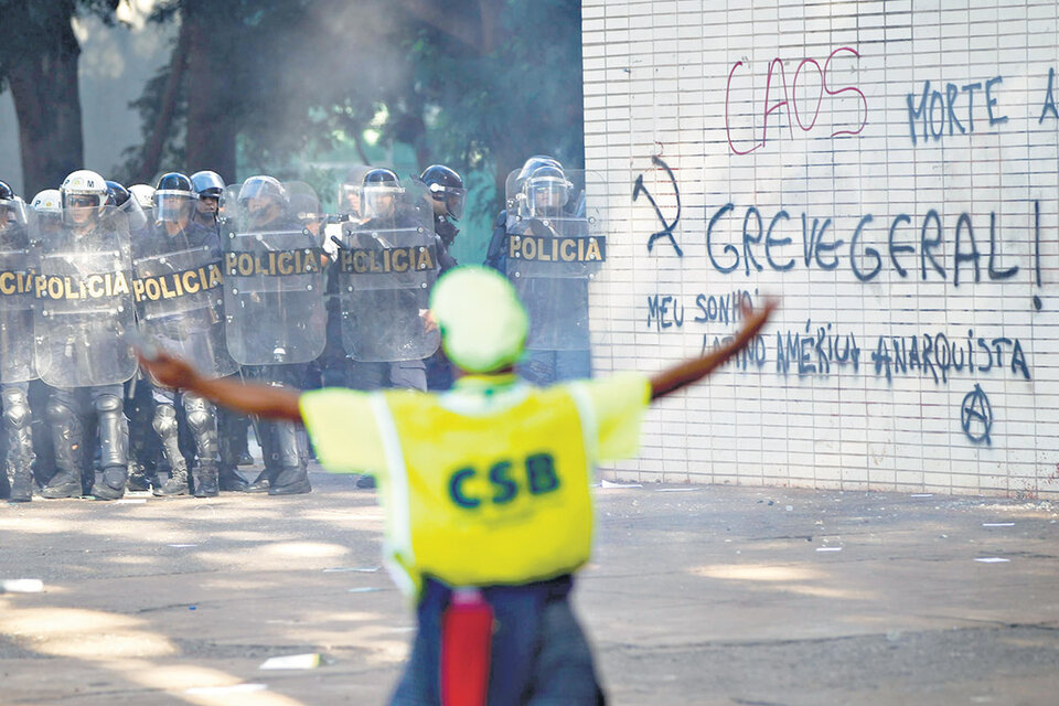 Manifestantes con los brazos en alto enfrentan a la policía antimotines en Brasilia. (Fuente: AFP)