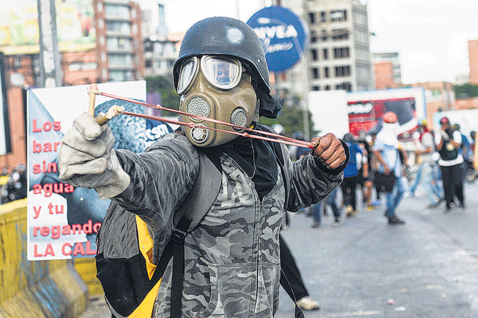 Un activista opositor usa una gomera durante una protesta contra el gobierno de Maduro.