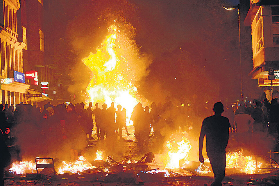 Manifestantes caminan entre barricadas incendiadas en el distrito de Schanzenvietel, de Hamburgo, Alemania.